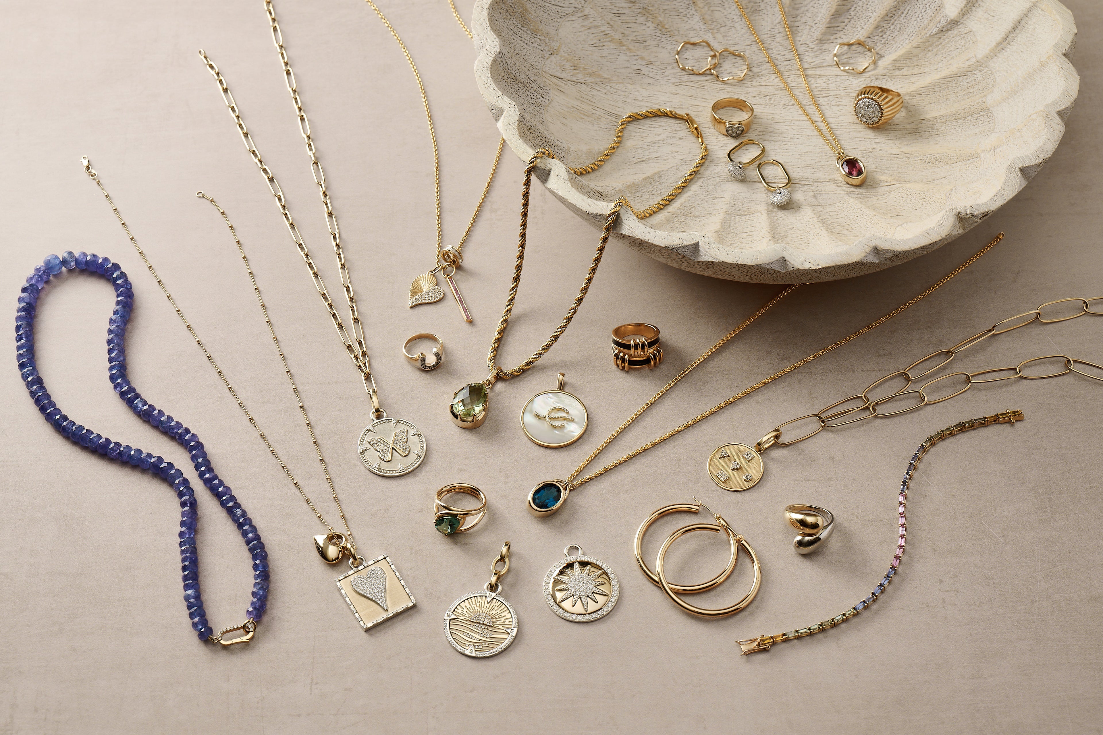 Collection of gold jewelry including necklaces, rings, and bracelets on a beige surface.