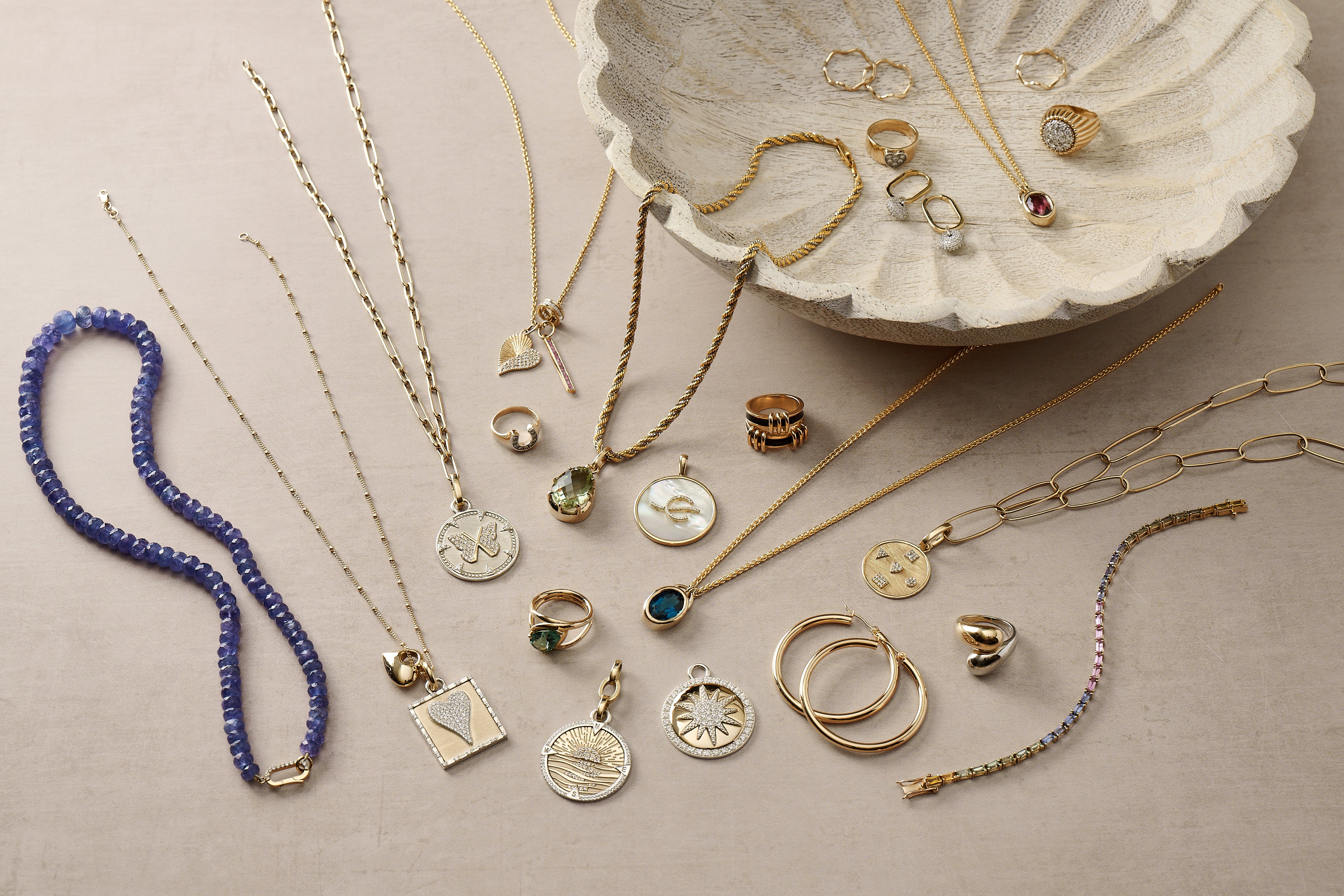 Collection of gold jewelry including necklaces, rings, and bracelets on a beige surface.