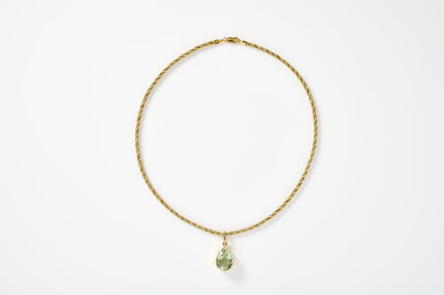 Gold necklace with a green pendant on a white background
